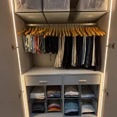 A beautifully organized closet featuring wooden hangers for trousers and clear dividers for folded clothes. Using consistent hangers and storage solutions creates a clean, streamlined look that is simple to maintain.