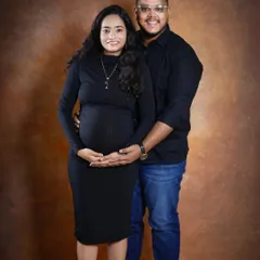 A warm and classic studio portrait of the couple. They stand together, both looking at the camera, creating a beautiful formal memory of their pregnancy.
