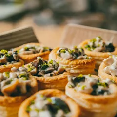 We take pride in our gourmet vegetarian offerings. This close-up shows our Creamy Mushroom Vol-au-vents, a sophisticated bite-sized appetizer filled with a rich, savory mushroom filling, perfect for adding a touch of elegance.