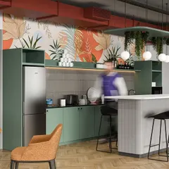 A vibrant office pantry designed to be a hub of activity. The space features green cabinetry, a breakfast bar, comfortable seating, and a botanical wallpaper that adds a playful and energetic touch.