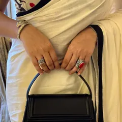 It's all in the details. A close-up of my hands holding the structured bag, showing off the statement rings that add a pop of color and personality to this date night outfit.