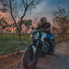 A beautiful shot of our Dominar 400 against the backdrop of a colorful sunset and lush green fields.