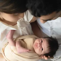 A precious moment of connection as a newborn, held by their parents, looks up with wide-eyed wonder. It's a beautiful glimpse into their developing personality.