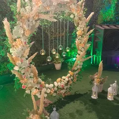A rustic yet elegant photo booth for an outdoor party. This circular wreath is made with pampas grass and pastel flowers, with hanging crystal globes for a magical touch.