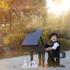 A joyful moment at the piano. The warm, natural lighting and the baby's happy expression make this a standout portrait from the first birthday shoot.