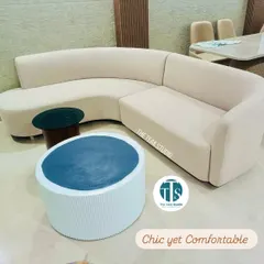 Chic yet comfortable, this custom L-shaped sofa in a neutral beige fabric is perfect for modern living rooms. Its clean lines and curved corner create a welcoming and stylish seating area, paired here with our fluted and cylindrical center tables.