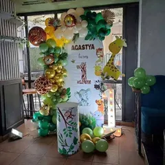 A safari adventure for Agastya's first birthday. This setup features a personalized backdrop with jungle animals, an organic balloon garland with animal-print balloons, and a light-up number '1'.