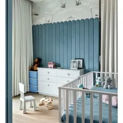 A full view of Rockstar Remy's nursery. The room features midnight blue padded walls that are nano-coated for safety, a soft wooden floor, and a custom cot. The pandas on hot air balloons wallpaper adds a touch of whimsy.