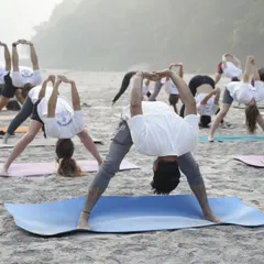 A group session on the beach, where we are all practicing a wide-legged forward bend. Practicing outdoors adds a different dimension to our yoga, helping us feel more grounded and connected to the environment.
