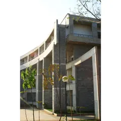The curved hostel block at IIM-B, designed in two phases. The building's form wraps around a playground and preserves existing trees, creating a unique relationship between the architecture and the landscape.