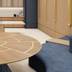 A render of a collaborative lounge area, featuring a custom curved sofa in a rich blue fabric and a bespoke coffee table with brass inlay. This zone is designed to encourage spontaneous conversations and team interaction in a comfortable, relaxed setting.