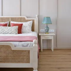 A close-up of the French-inspired bed in the 'House of Kismish' project, featuring a classic design with turned legs and cane weaving on the headboard and footboard.