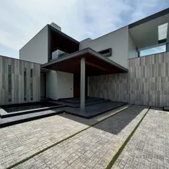 The entrance to Rosewood Farmhouse is designed for a grand arrival. A wide, oversized covered porch is supported by a single column, creating a powerful architectural statement. The cobblestone driveway and integrated water feature add layers of texture and tranquility.