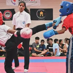 Precision in action. Here, one of our kickboxing students executes a powerful high kick during a competitive match. Our training focuses on developing the speed, technique, and confidence needed to perform effectively under pressure.