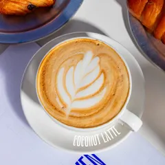 Our hot Coconut Latte, expertly prepared with beautiful latte art. It's a creamy, subtly sweet coffee made with a double espresso, coconut syrup, and condensed milk.