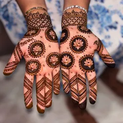 A symmetrical design perfect for festivals, featuring bold lotus motifs in circles on both palms. The fingers are decorated with geometric lines, and the name 'Shivam' is subtly included on one hand.