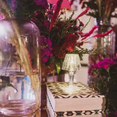 A tiny crystal lamp placed on a stack of beautifully patterned books adds a touch of whimsy and sophistication to this floral arrangement.