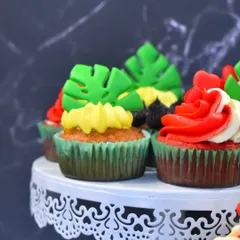 A close-up of the vibrant cupcakes made by students in my masterclass. This selection includes tropical pineapple with a fondant leaf and a rich red velvet.