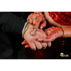 A close-up shot of the couple's hands, showcasing their engagement rings and the bride's beautiful henna.