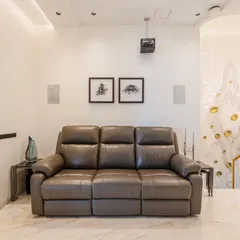 The home theater features comfortable leather recliners and is acoustically designed for an immersive sound experience. The clean white walls and marble floor keep the look sophisticated.