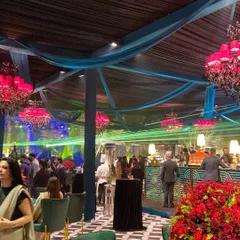 A wide view of a lavish wedding reception, with our bar and food stations seamlessly integrated into the stunning decor of teal and magenta.