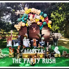 This rustic woodland jungle theme for Agastya's first birthday combines the wildness of the jungle with a charming forest feel. The setup features a variety of animal cutouts, from tigers and elephants to deer, set against a backdrop of wooden panels and lush greenery.