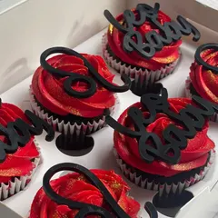 A three-quarter view of the Leo cupcakes, highlighting the height of the buttercream swirls and how the black toppers stand out against the red.