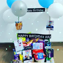 A great example of a budget-friendly birthday hamper that still feels special. It's filled with a variety of Dairy Milk chocolates and other snacks, and personalized with photos and balloons for a 'Jiju'.