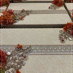 A close-up of the detailed craftsmanship on my trousseau boxes. The rich, textured fabric is adorned with a band of traditional silver embroidery and a corner piece of flowers, mirrors, and crystals.