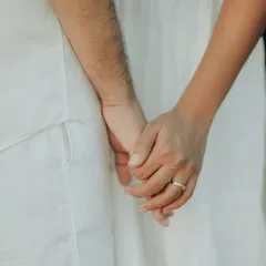 A simple, powerful shot of a couple holding hands. This close-up focuses on their intertwined fingers and the wedding ring, symbolizing their bond.
