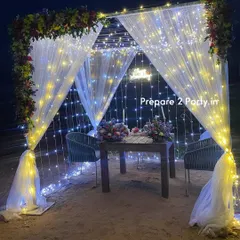 This romantic dining setup features a cabana draped in sheer white fabric and wrapped in warm and cool fairy lights. It's the perfect private setting for an anniversary or proposal dinner.