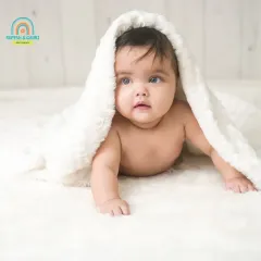 Peek-a-boo. This adorable twin is playing under a fluffy white blanket, her bright eyes looking right at the camera.