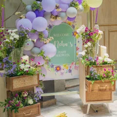Welcome your guests in style. ✨ I love creating personalized entryways like this one, featuring a custom welcome sign for 'Neha's Baby Shower' framed by cascading balloons and unique floral arrangements spilling from rustic wooden drawers.
