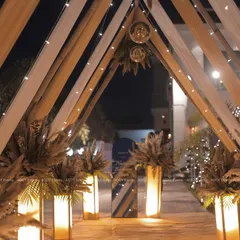 A bohemian-glam themed entrance featuring a canopy of white and beige drapes, pampas grass arrangements, and disco balls. This creative design is perfect for a relaxed yet stylish corporate party or team celebration.