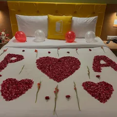 For a special romantic gesture, I can arrange rose petals on the bed to spell out names or initials, like 'P' and 'A' here, surrounded by hearts. It's a personal touch that makes the surprise unique.