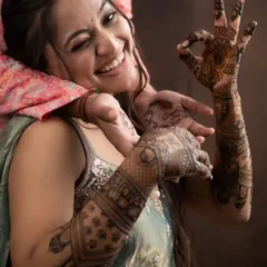 The pure joy of a bride with her freshly done mehandi. Her playful wink and the 'OK' sign say it all. This is the happiness we strive for.