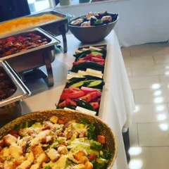 A close-up of our buffet spread, featuring fresh Caesar salad, a vegetable platter, and hot dishes in chafing trays. We offer a balanced menu with both hot and cold options.