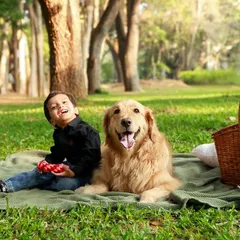 The grass has never been greener, and the smiles have never been bigger. A perfect picnic scene with a boy and his best friend, this shot captures the simple joys of childhood with a pet.
