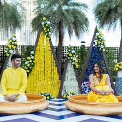 A modern and geometric Haldi setup. We used triangular backdrops with marigold strings and pops of blue for a fresh and contemporary take on the traditional ceremony.