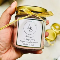 We love making your wedding favors feel personal. This is a close-up of a scented soy candle we customized with the couple's initials and a thank you message, finished with a delicate golden ribbon.
