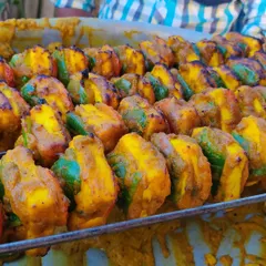 A tray full of perfectly cooked paneer tikka skewers, ready to be served to guests straight from the live tandoor counter.