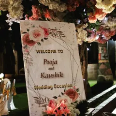 This close-up shows the welcome sign nestled under a tree decorated with flowers. Integrating signage with the venue's natural elements is a detail I focus on.