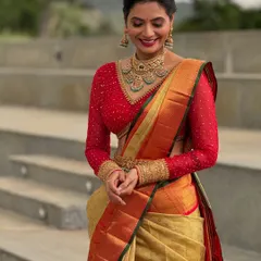 I love creating striking contrasts. Here, a custom red net blouse with full-length embroidered sleeves brings a bold, modern feel to a classic gold Kanchivaram saree, perfect for a wedding reception or engagement.
