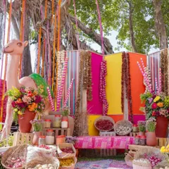 A truly unique mehendi setup inspired by a Rajasthani bazaar. The vibrant colors, camel prop, and rustic elements like spice jars and baskets create an immersive and unforgettable cultural experience.