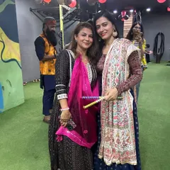 Two members show off their colorful dandiya sticks and traditional attire during our Navratri celebration.
