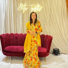 A full-length view of my floral sharara outfit in front of a "Better Together" neon sign. It's always a joy to be part of such happy occasions.