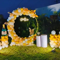 An outdoor bridal shower setup featuring a beautiful circular balloon arch. The yellow and white color scheme is perfect for a daytime event, and the neon sign adds a modern touch for evening celebrations.