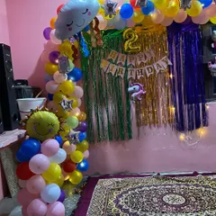A cheerful and colorful home decoration for a second birthday. This theme includes a rainbow balloon arch with cute sun and cloud foil balloons.