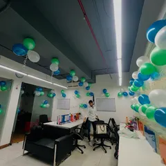 The entire office space is filled with balloon clusters hanging from the ceiling, creating a fun and celebratory atmosphere for a team event.