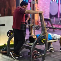 Safety is our top priority, especially during heavy lifts. A trainer carefully spots a client during a bench press, providing the confidence to push for that extra rep.